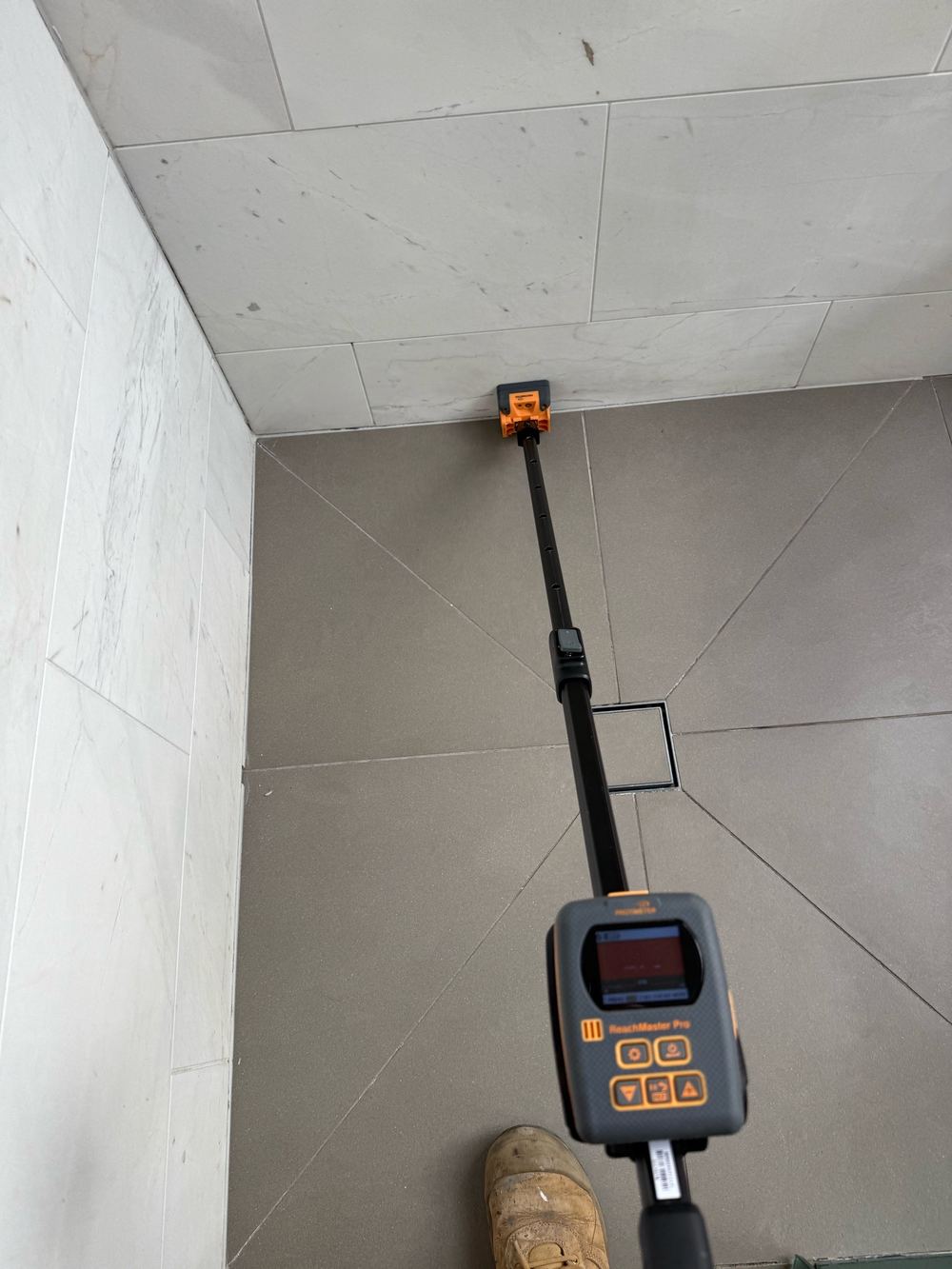 Moisture meter reading water behind tiles where the grout has failed, found during a building and pest inspection in Hawthorn